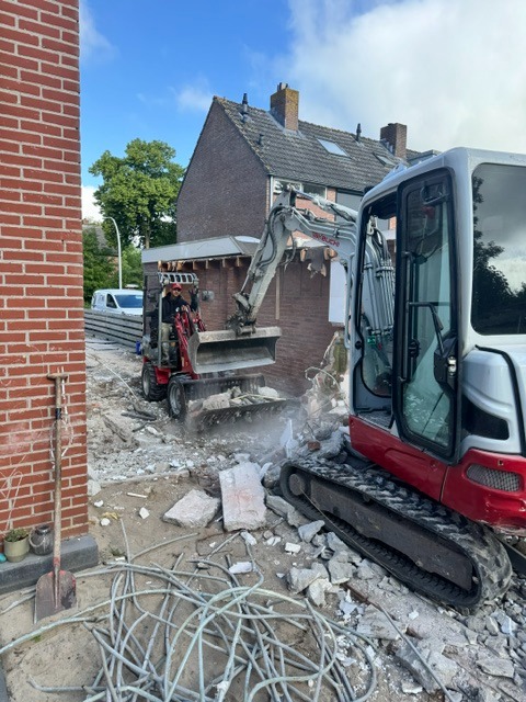 Twee compacte graafmachines verwijderen gecontroleerd een gemetselde aanbouw
