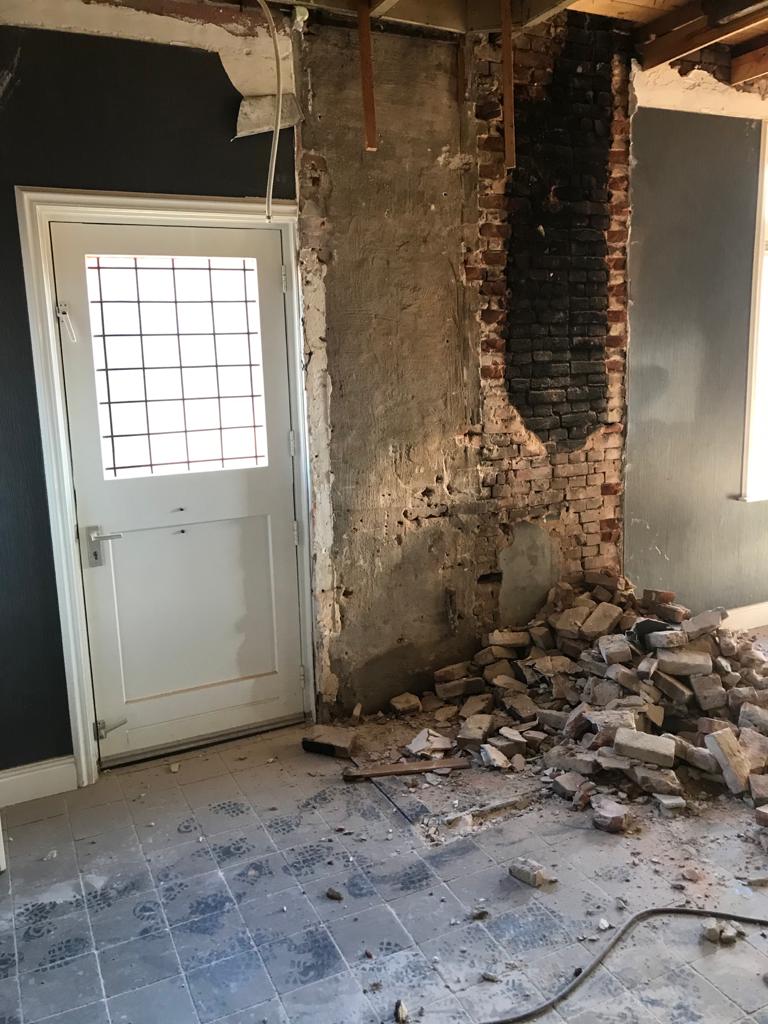 Binnenwand tijdens renovatiesloop met vrijgelegd metselwerk en puin