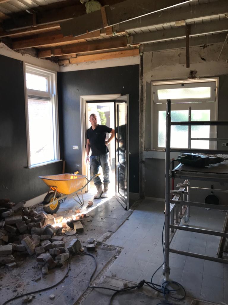 Vakman voert selectieve sloop uit in een woning met gestut plafond en gescheiden puin