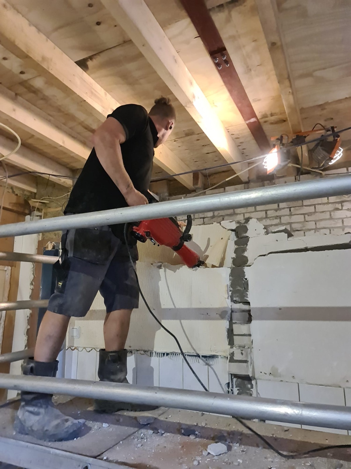 Vakman verwijdert gecontroleerd metselwerk vanaf een veilige werksteiger